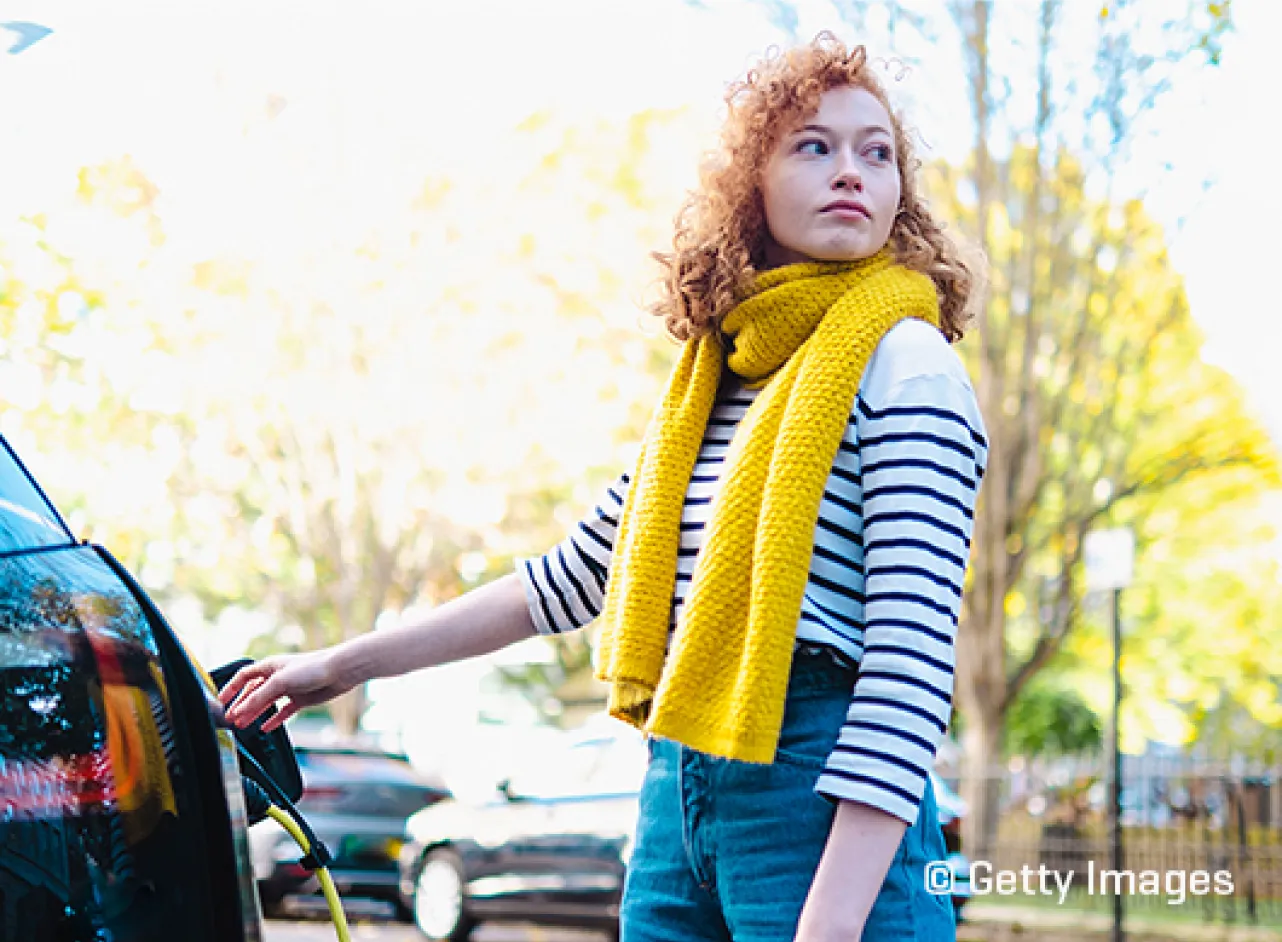Vrouw met gele sjaal laadt elektrische auto op